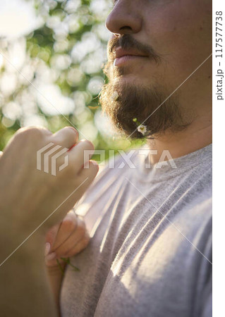 the wife weaves flowers into her husband's beard 117577738