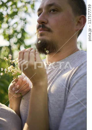 the wife weaves flowers into her husband's beard the wife weaves flowers into her husband's beard 117577739