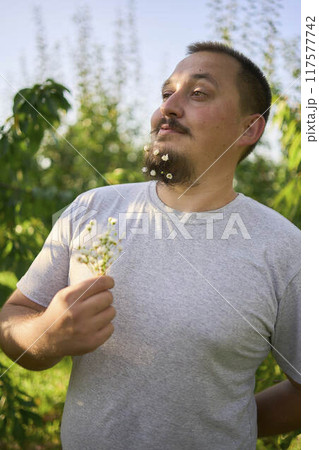 a man laughs at the flowers in his beard that his wife has woven into him 117577742