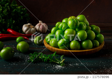 Tkemali, green cherry plum, with ingredients for sauce, on a wooden table, close-up, rustic, food background, no people, selective focus, 117578096