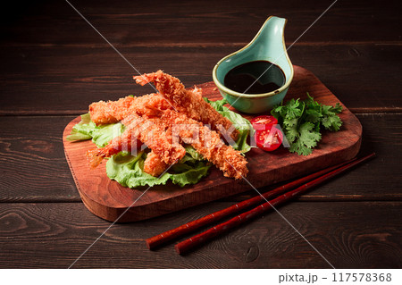 Fried shrimp, peeled in tempura, soy sauce, close-up, on a wooden board, 117578368