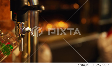 Close-up of shiny beer tap with handle and mirror, set against blurred background, and empty glasses in the background. Coziness in bar Close-up of shiny beer tap with handle and mirror, set against blurred background, and empty glasses in the background. Coziness in bar 117578582