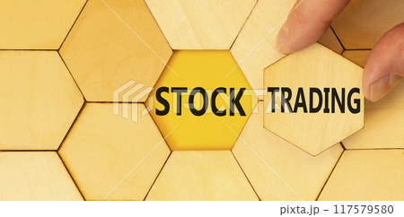 Stock trading symbol. Concept words Stock trading on beautiful wooden puzzle. Beautiful yellow table yellow background. Businessman hand. Business stock trading concept. Copy space. Stock trading symbol. Concept words Stock trading on beautiful wooden puzzle. Beautiful yellow table yellow background. Businessman hand. Business stock trading concept. Copy space. 117579580