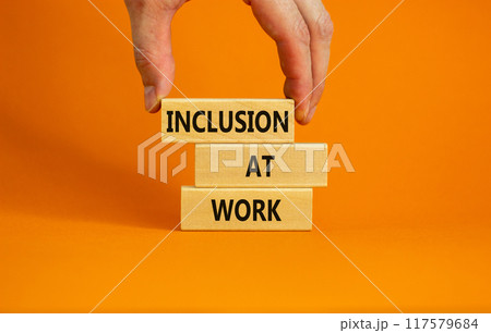 Inclusion at work symbol. Wooden blocks with words 'Inclusion at work' on beautiful orange background. Businessman hand. Business, inclusion at work concept. Copy space. Inclusion at work symbol. Wooden blocks with words 'Inclusion at work' on beautiful orange background. Businessman hand. Business, inclusion at work concept. Copy space. 117579684