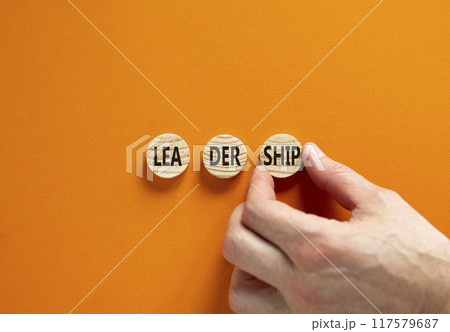 Leadership symbol. Concept word Leadership on beautiful wooden circles. Businessman hand. Beautiful orange background. Business leadership concept. Copy space. Leadership symbol. Concept word Leadership on beautiful wooden circles. Businessman hand. Beautiful orange background. Business leadership concept. Copy space. 117579687
