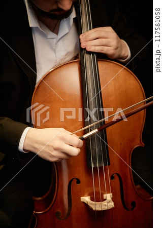 Vertical cropped shot of unrecognizable male classical music artist playing cello with bow Vertical cropped shot of unrecognizable male classical music artist playing cello with bow 117581058