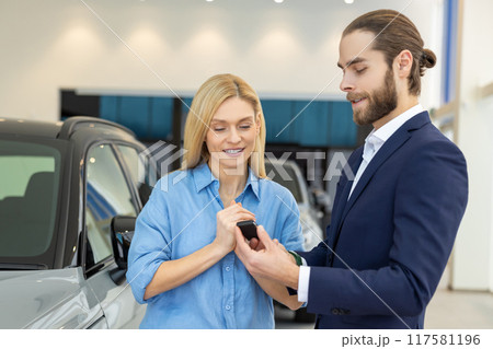 Female choosing new car with the assistance of male business consultant at auto dealership 117581196