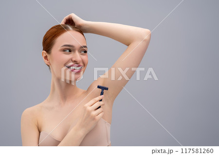 Young red-haired girl shaving her armpit with razor hand Young red-haired girl shaving her armpit with razor hand 117581260