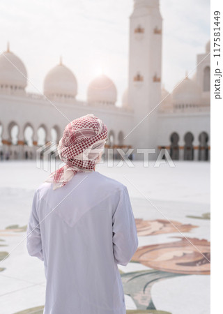 Man standing in awe at grand mosque courtyard with intricate designs Man standing in awe at grand mosque courtyard with intricate designs 117581449