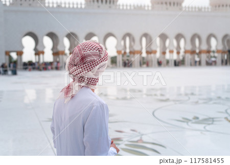Man standing in awe at grand mosque courtyard with intricate designs Man standing in awe at grand mosque courtyard with intricate designs 117581455