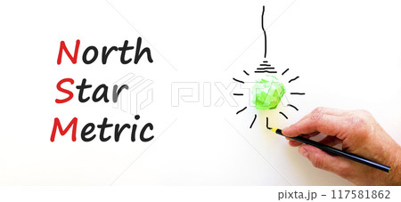 NSM north star metric symbol. Concept words NSM north star metric on white paper on a beautiful white background. Businessman hand. Business and NSM north star metric concept. Copy space. 117581862