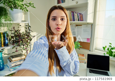Selfie portrait of teenage cheerful female looking at web camera Selfie portrait of teenage cheerful female looking at web camera 117581969