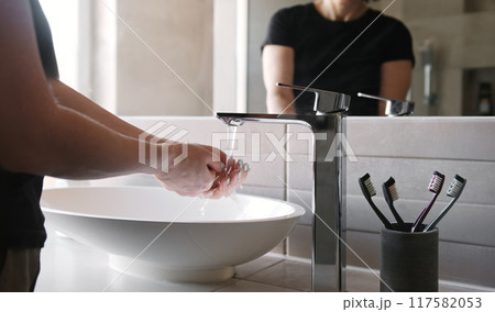 Woman In The Mirror Reflection Washing Her Hands In The Bathroom 117582053