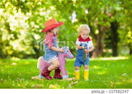 Cowboy kids playing with toy horse Cowboy kids playing with toy horse 117582247