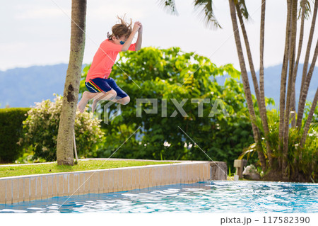 Kids jump into swimming pool. Summer water fun. 117582390