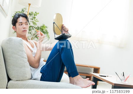 リビングでメイクをする若い男性 リビングでメイクをする若い男性 117583199