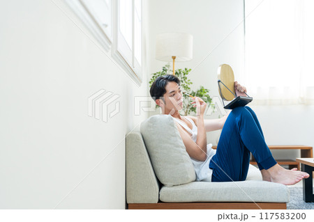 リビングでメイクをする若い男性 117583200