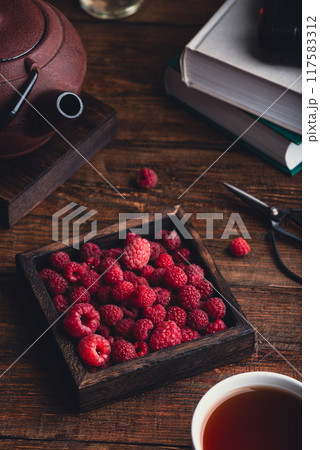 Raspberries and a cup of tea on a table. 117583312