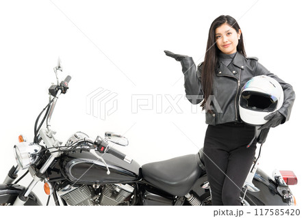 バイクの横に立って、ヘルメットを持って、指差しするバイク女子 バイクの横に立って、ヘルメットを持って、指差しするバイク女子 117585420