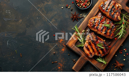 Juicy meat steak with herbs and spices on a wooden board on a dark background with space for text Juicy meat steak with herbs and spices on a wooden board on a dark background with space for text 117586043