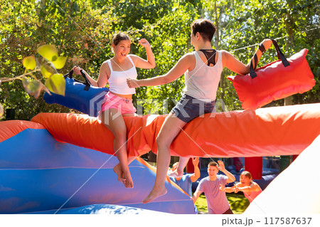 Women having pillow fight between each other in outdoor amusement park 117587637