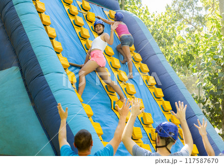 Women trying to climb on top of slide in amusement park 117587670