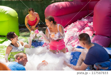 Cheerful men and women playing in foam pool in amusement park 117587833