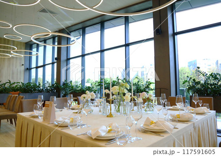 Table setting in a restaurant. Empty glasses set in restaurant. Table setting with glasses, cutlery and plates. Restaurant interior. 117591605