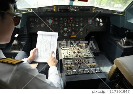 Cropped shot of pilot dressed in a uniform preparing for flight in the cockpit of an aircraft 117591947