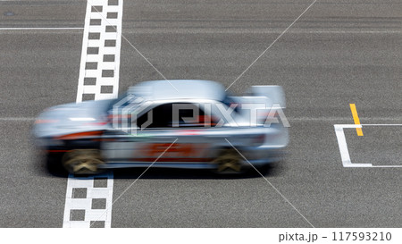 Motion blur race car racing on speed track, Car race on the international circuit race track crossing start and finish line, Race car crossing start and finish line, Target business achieve victory. Motion blur race car racing on speed track, Car race on the international circuit race track crossing start and finish line, Race car crossing start and finish line, Target business achieve victory. 117593210