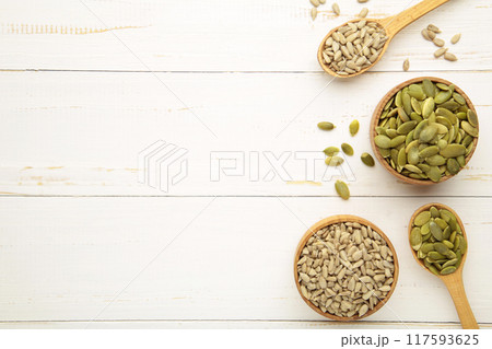 Pumpkin and sunflower seeds on spoon on white wooden background. 117593625