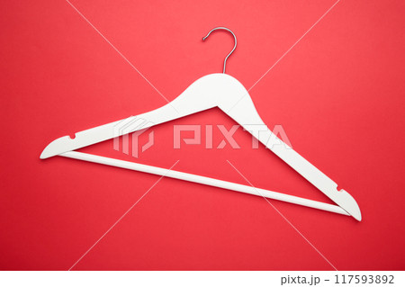 One wooden white hanger on red background. 117593892