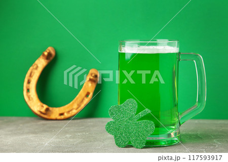 Glass of beer and horseshoe for St Patricks day on green background. 117593917
