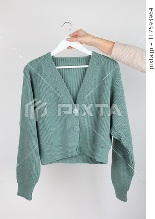 Soft sweaters for women on wooden hangers in hand. 117593964