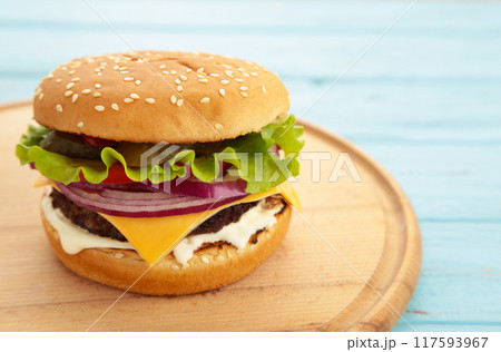 Fresh homemade burger on cutting board on blue wooden table. Fresh homemade burger on cutting board on blue wooden table. 117593967