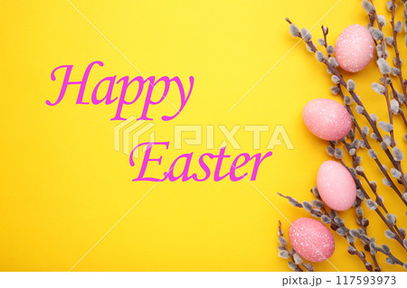 Pink easter eggs and willow branches on yellow background Pink easter eggs and willow branches on yellow background 117593973