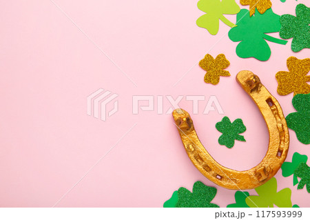 Green clovers and gold horseshoe on pink background for St. Patrick's Day Holiday. 117593999