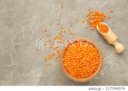 Red lentils in a wooden spoon and bowl on grey background. 117594074