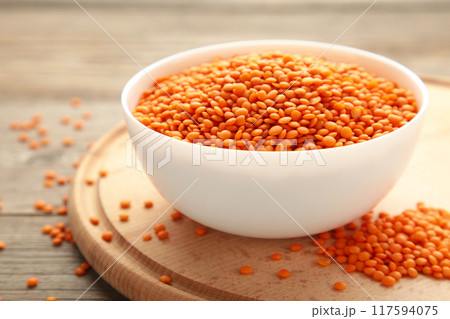 Red lentils in white bowl on a grey wooden table. 117594075