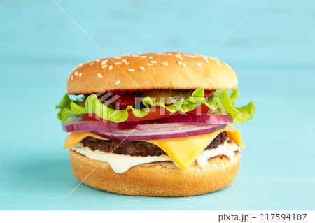 Homemade hamburger with vegetables on blue background. Homemade hamburger with vegetables on blue background. 117594107