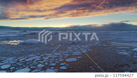 Arctic frozen ocean winter sunset landscape aerial view. Ice floes and snow covered icebergs under bright colorful evening sky. Antarctica travel and exploration. Discover the beauty of South Pole Arctic frozen ocean winter sunset landscape aerial view. Ice floes and snow covered icebergs under bright colorful evening sky. Antarctica travel and exploration. Discover the beauty of South Pole 117594427