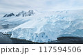 Blue snowy glacier towering Antarctica coastline. Snow covered giant iceberg ice wall rises above cold, dark ocean water. Antarctic winter polar landscape panorama. Aerial cinematic ecology scene 117594506