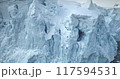 Close up calving glacier ice cliff dominates polar ocean. Towering blue snow wall mountain in background. Natural wild scene, winter wallpaper. Ecology, melting ice, climate change and global warming 117594531