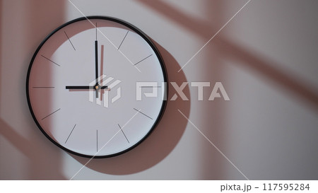 Elegant Black Clock Showing 21.00/09.00 with Shadows on Minimalist Wall - Ideal for Time Management and Interior Design Promotions Elegant Black Clock Showing 21.00/09.00 with Shadows on Minimalist Wall - Ideal for Time Management and Interior Design Promotions 117595284