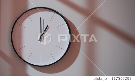 Elegant Black Clock Showing 13.00/01.00 with Shadows on Minimalist Wall - Ideal for Time Management and Interior Design Promotions Elegant Black Clock Showing 13.00/01.00 with Shadows on Minimalist Wall - Ideal for Time Management and Interior Design Promotions 117595292