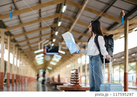 A woman is standing in a train station with a map in her hand 117595297