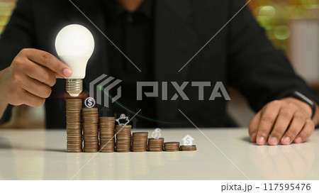Businessman holding glowing light bulb with virtual hologram. Investment and business Innovation ideas concept Businessman holding glowing light bulb with virtual hologram. Investment and business Innovation ideas concept 117595476