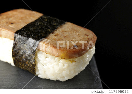 スレートプレートに乗ったスパムむすびを黒背景で撮影 117596032