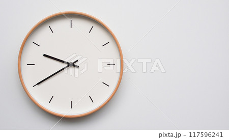 Minimalist wooden Wall Clock on White Wooden Surface with Space for Text.  Time Set at 21.40/09.40 117596241
