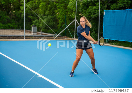 Professional female tennis player playing in tennis with racket and ball on outside court 117596487